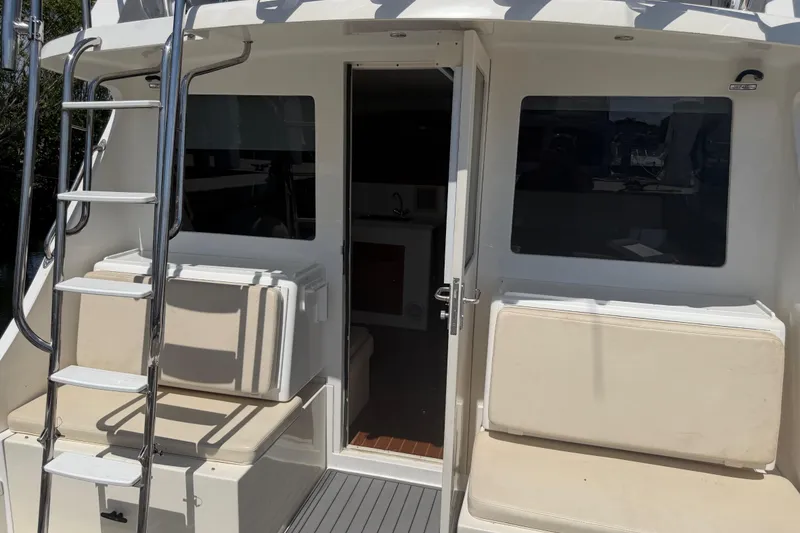 Slide: The Image of 2000 Cabo 35 Flybridge boat with ladder, seating, and open cabin door. - 55