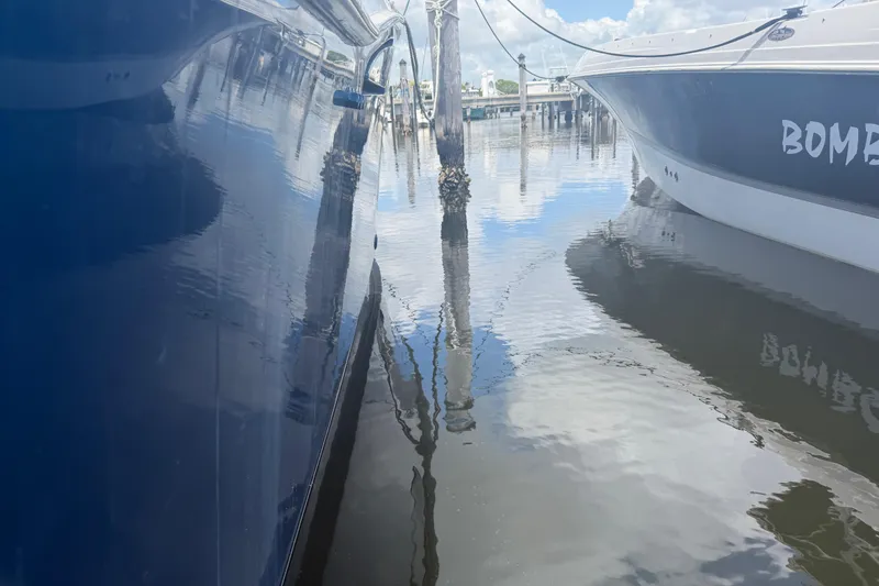 Slide: The Image of Two boats docked in calm water, reflecting a clear sky and marina surroundings. - 24