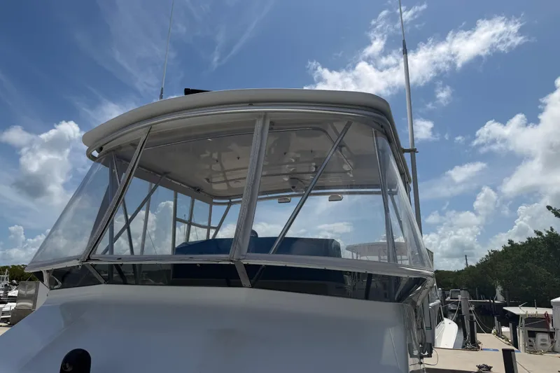 Slide: The Image of 2000 Cabo 35 Flybridge boat with clear enclosure, docked under a blue sky. - 40