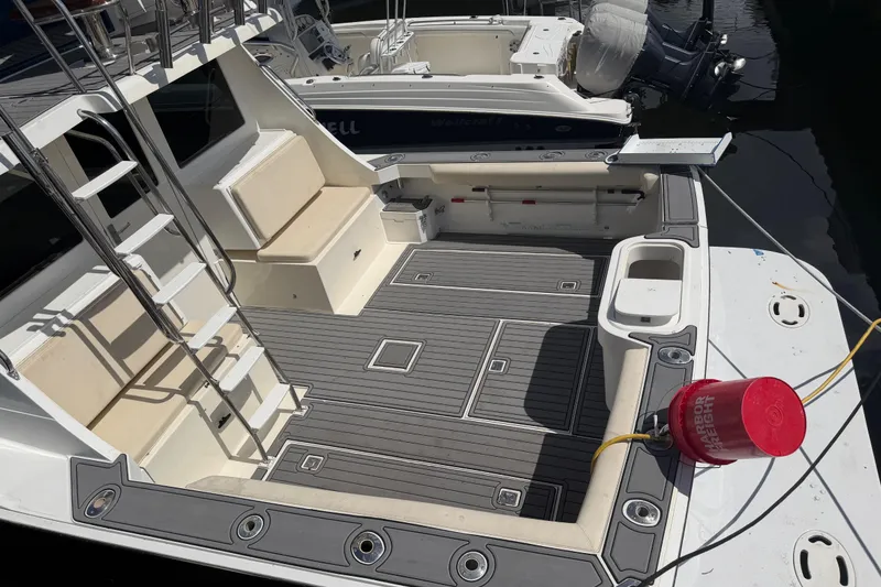 Slide: The Image of 2000 Cabo 35 Flybridge boat deck with seating and ladder, docked at marina. - 2