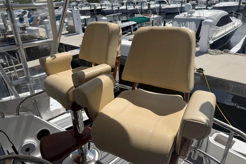 Slide: The Image of Two beige captain chairs on a 2000 Cabo 35 Flybridge at a marina. - 7