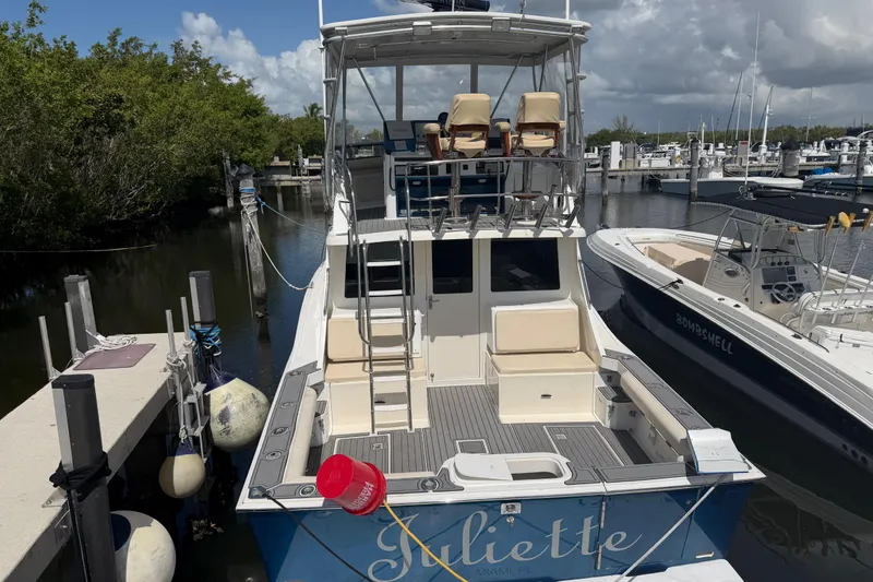 Slide: The Image of 2000 Cabo 35 Flybridge boat docked at marina, featuring spacious deck and flybridge seating. - 4
