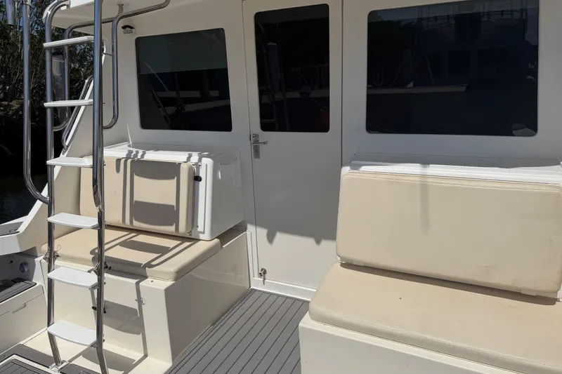 Slide: The Image of 2000 Cabo 35 Flybridge boat with ladder, cushioned seating, and cabin door. - 51