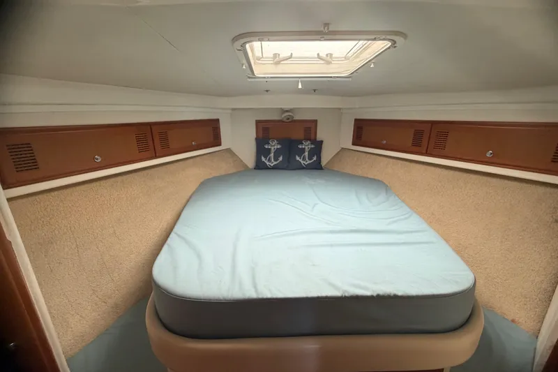 Slide: The Image of Cabo 35 Flybridge 2000 cabin interior with bed, anchor-themed pillows, and overhead hatch. - 81