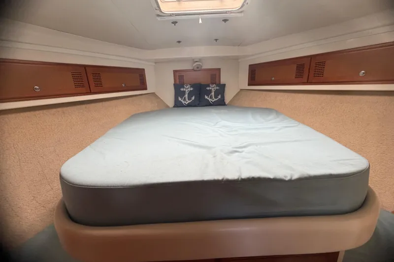Slide: The Image of Cabo 35 Flybridge 2000 interior cabin with bed and anchor-themed pillows. - 90