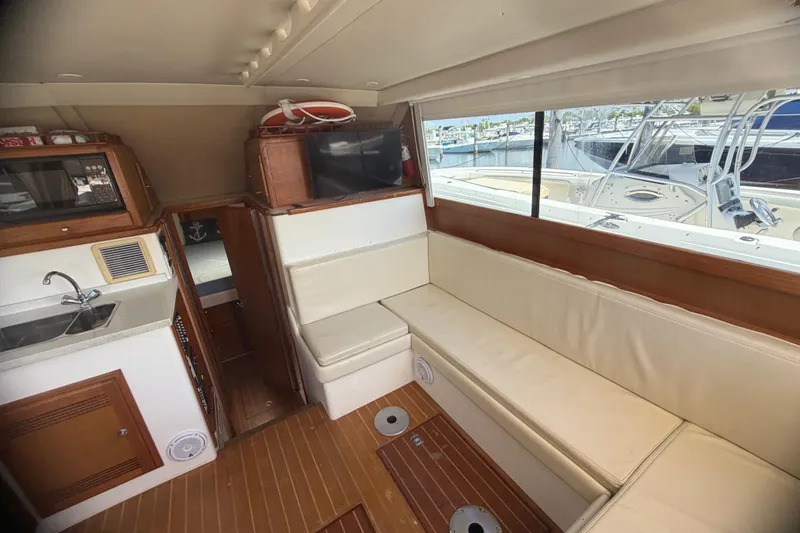 Slide: The Image of Interior of 2000 Cabo 35 Flybridge yacht with seating, kitchenette, and window view of marina. - 62