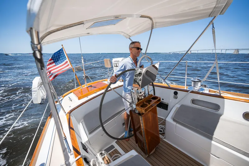Slide: The Image of Man steering 1985 Hinckley Sou'wester 51 sailboat on open water, American flag visible. - 5