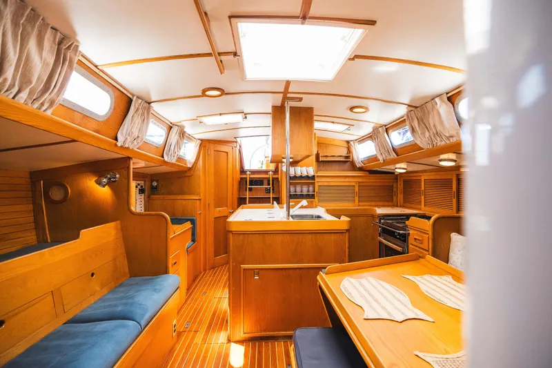 Slide: The Image of Interior of 1985 Hinckley Sou'wester 51 sailboat, featuring elegant woodwork and cozy seating. - 19