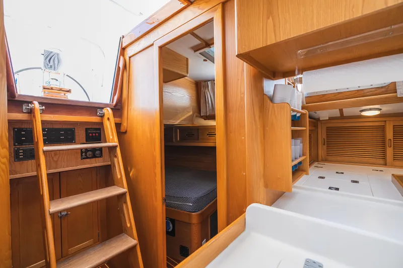 Slide: The Image of Interior of 1985 Hinckley Sou'wester 51 sailboat, featuring wooden cabinetry and cozy sleeping quarters. - 36