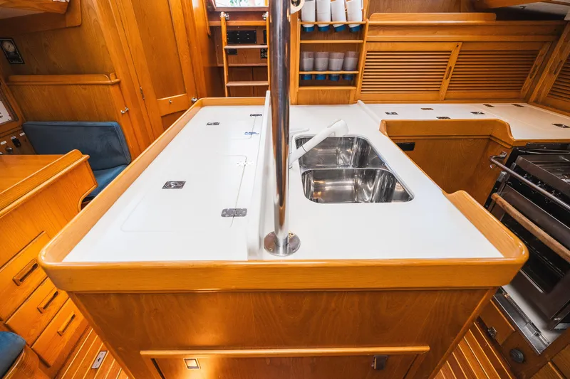 Slide: The Image of Interior of 1985 Hinckley Sou'wester 51 yacht, featuring a well-equipped galley with wooden cabinetry. - 11