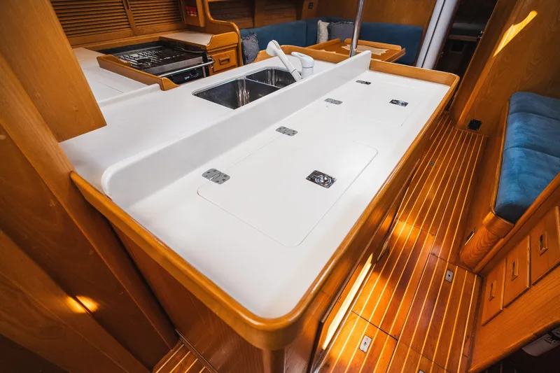 Slide: The Image of Interior of 1985 Hinckley Sou'wester 51 yacht, featuring a sleek kitchen and wooden flooring. - 9