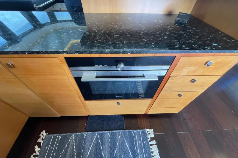 Slide: The Image of Modern kitchen with black granite countertop, wooden cabinets, and built-in oven on a Serenity 64 yacht. - 30