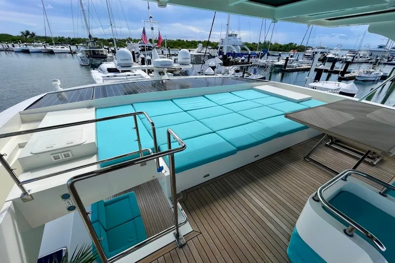 Slide: The Image of Luxurious Serenity 64 yacht deck with turquoise seating, solar panels, and marina view. - 13