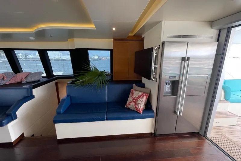 Slide: The Image of Luxurious yacht interior with blue seating, modern fridge, and ocean view windows, Serenity 64, 2018. - 31