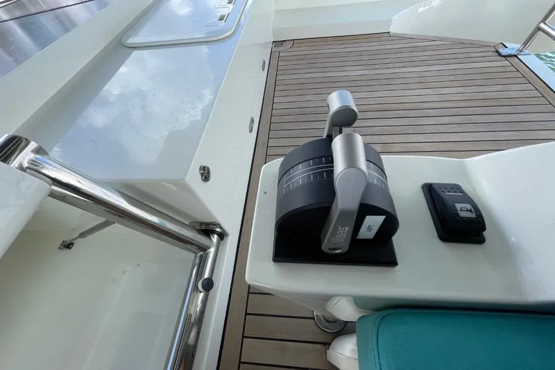 Slide: The Image of Control panel on a 2018 Serenity 64 yacht, featuring throttle levers and a wooden deck. - 22