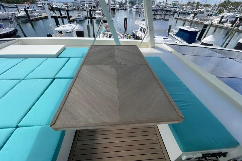 Slide: The Image of Luxurious Serenity 64 yacht deck with turquoise seating, wooden table, and marina view, 2018 model. - 16
