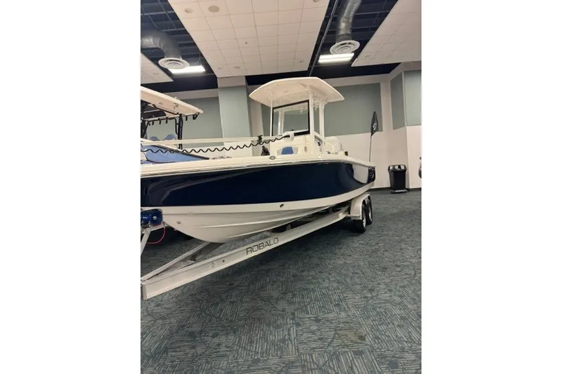 Slide: The Image of 2026 Robalo 246 Cayman boat displayed indoors on a trailer. - 1