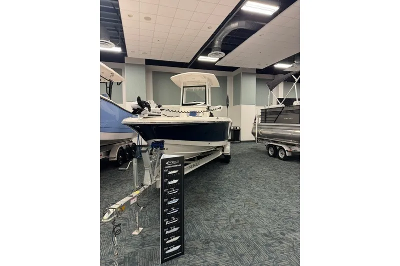 Slide: The Image of 2026 Robalo 246 Cayman boat displayed indoors at a showroom. - 2