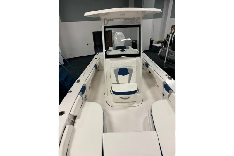 Slide: The Image of 2026 Robalo 246 Cayman boat interior with white and blue seating, under showroom lighting. - 8