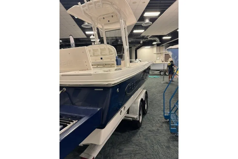Slide: The Image of 2026 Robalo 246 Cayman boat on display indoors, featuring a sleek blue and white design. - 5