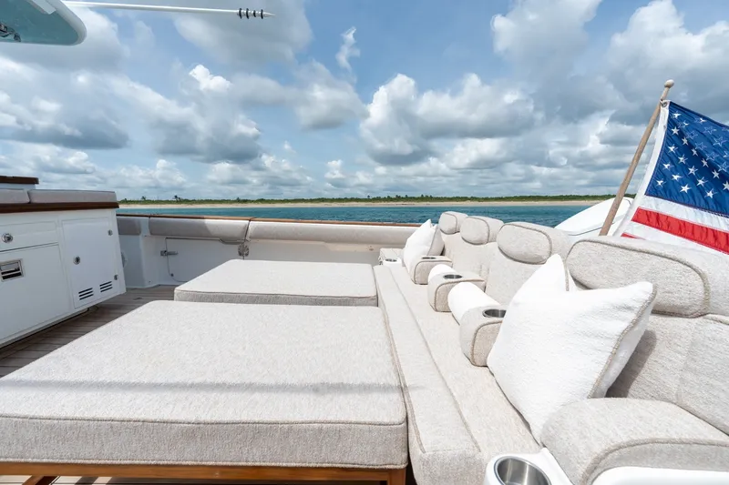 Slide: The Image of Luxurious seating on 2023 HCB 65 Estrella yacht with American flag, under a cloudy sky. - 51