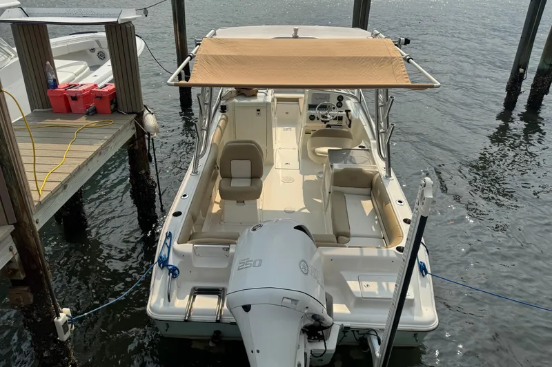 Slide: The Image of A 2019 Key West 239 DFS boat docked. It features a sunshade and an outboard motor. - 1