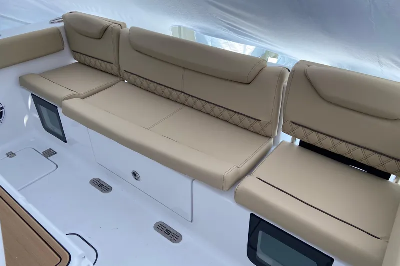 Slide: The Image of 2027 Sportsman Heritage 261 Center Console boat seating with beige upholstery and storage compartments. - 2
