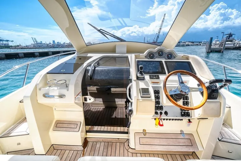 Slide: The Image of 2018 Chris-Craft Launch boat cockpit with wooden steering wheel and modern controls, docked at marina. - 1