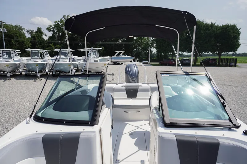 Slide: The Image of 2026 Chaparral 21 SSi OB boat with black canopy, parked in a gravel lot. - 9