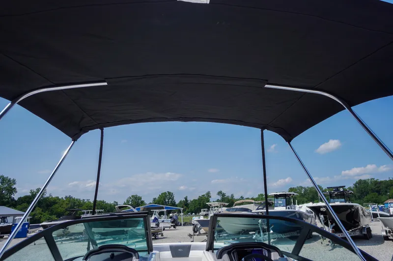 Slide: The Image of 2026 Chaparral 21 SSi OB boat with bimini top, parked outdoors under blue sky. - 49