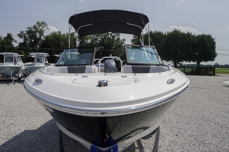 Slide: The Image of 2026 Chaparral 21 SSi OB boat with sleek design, parked outdoors on gravel. - 48