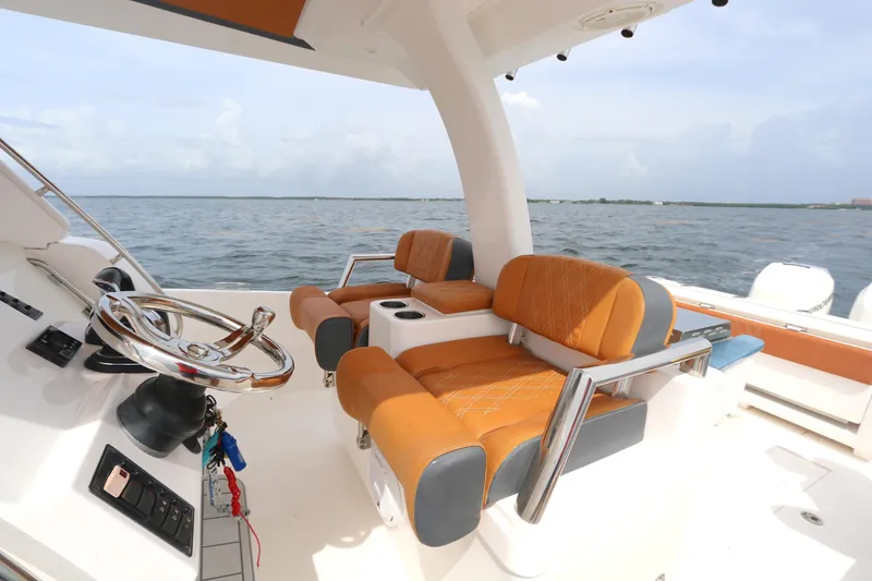 Slide: The Image of 2018 Belzona 327 Walkaround boat interior with orange seating and steering wheel, on open water. - 2