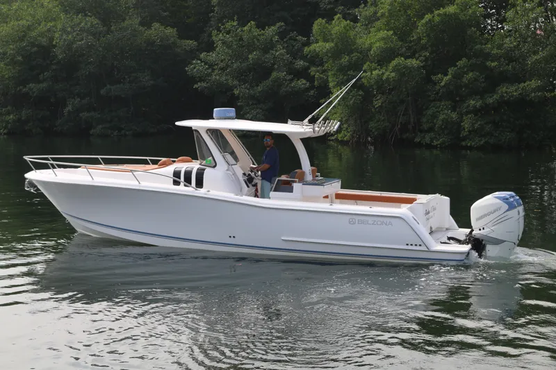 The Image of 2018 Belzona 327 Walkaround boat cruising on a calm lake with lush greenery. - 0