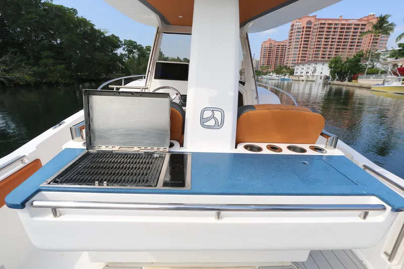Slide: The Image of 2018 Belzona 327 Walkaround boat with outdoor grill and seating, docked near waterfront buildings. - 8