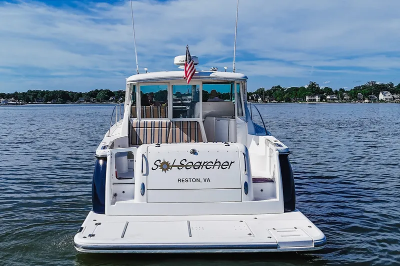 Slide: The Image of 2004 Tiara Yachts 4400 Sovran on calm water, rear view with "Sol Searcher" name. - 6