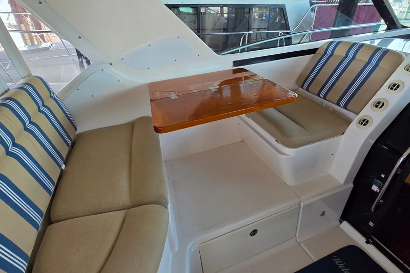 Slide: The Image of Interior seating area of 2004 Tiara Yachts 4400 Sovran with striped cushions and wooden table. - 19