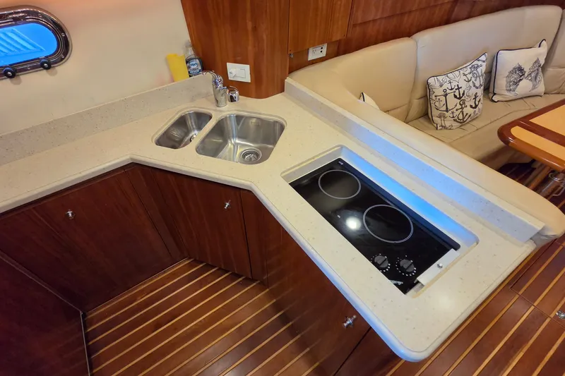 Slide: The Image of 2004 Tiara Yachts 4400 Sovran galley with dual sink, cooktop, and seating area. - 32