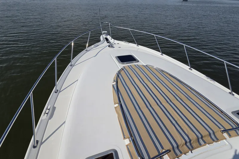 Slide: The Image of 2004 Tiara Yachts 4400 Sovran yacht deck with striped sun pad on calm water. - 8