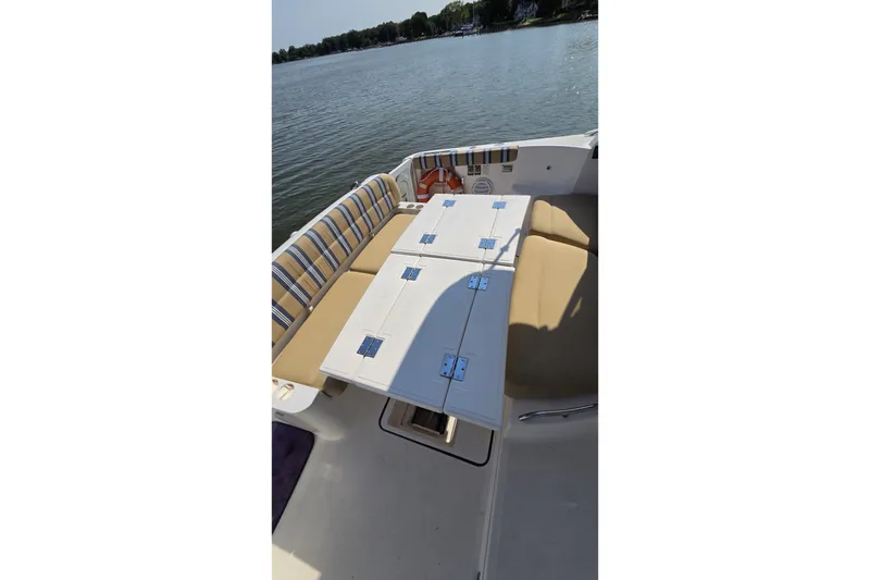 Slide: The Image of 2004 Tiara Yachts 4400 Sovran deck with cushioned seating and table, overlooking serene water. - 17