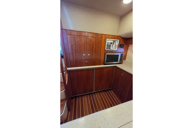 Slide: The Image of 2004 Tiara Yachts 4400 Sovran galley with wood cabinetry, microwave, and coffee maker. - 33
