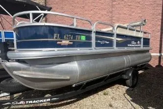 The Image of 2023 Sun Tracker Bass Buggy 18 DLX pontoon boat on trailer, parked outdoors. - 0