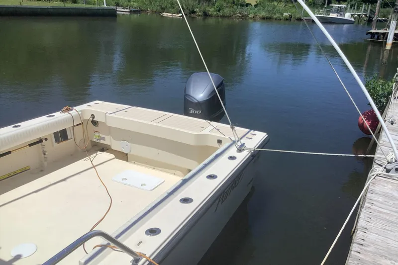 Slide: The Image of 2012 Parker 2520 XL Sport Cabin boat docked on calm water with outboard motor. - 2