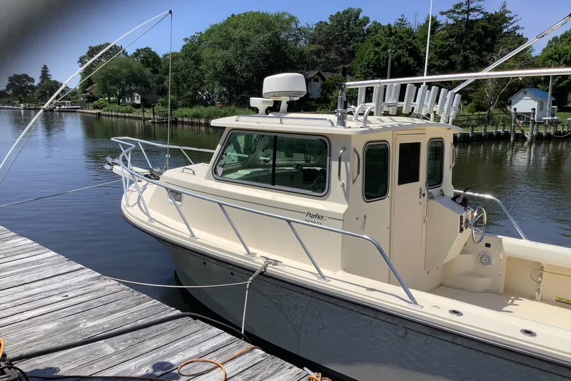 Slide: The Image of 2012 Parker 2520 XL Sport Cabin boat docked by a serene riverside. - 1