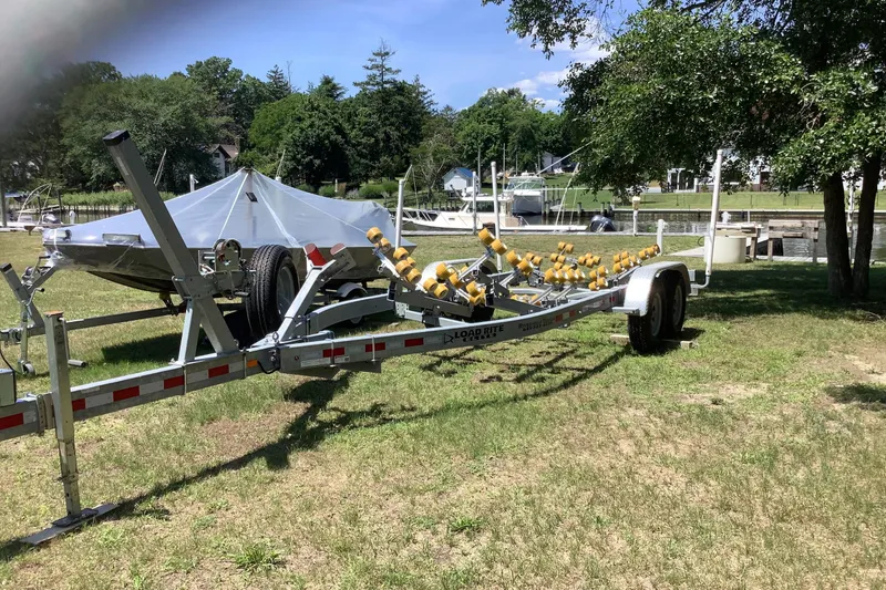 Slide: The Image of Trailer with a covered Parker 2520 XL Sport Cabin boat, 2012 model, parked on grass. - 18