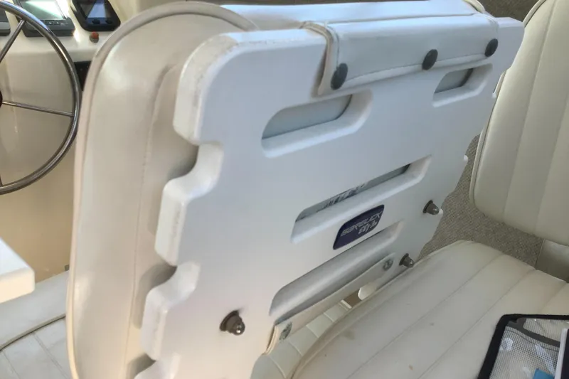 Slide: The Image of Interior of a 2012 Parker 2520 XL Sport Cabin boat, featuring white seating and steering wheel. - 14