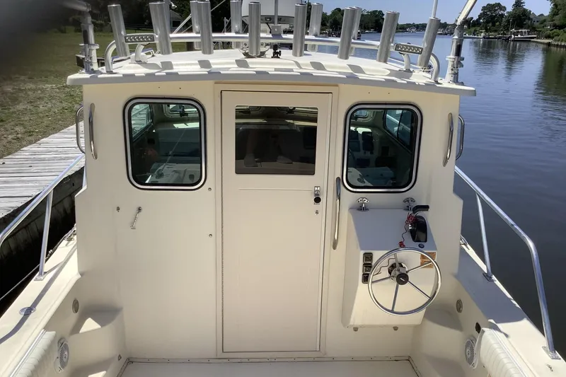 Slide: The Image of 2012 Parker 2520 XL Sport Cabin boat docked by a calm river. - 8
