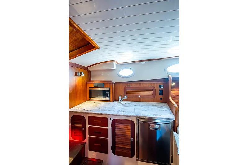 Slide: The Image of Interior of 2013 Hinckley Talaria 34 yacht, featuring a compact kitchen with wood accents. - 12