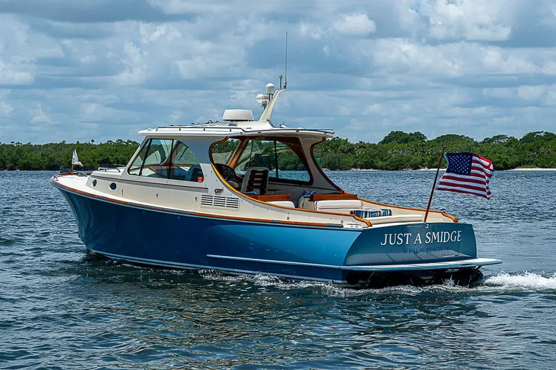 The Image of 2013 Hinckley Talaria 34 yacht named "Just A Smidge" cruising on water with American flag. - 0