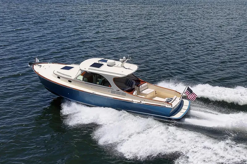 Slide: The Image of 2013 Hinckley Talaria 34 cruising on open water, displaying sleek design and American flag. - 20