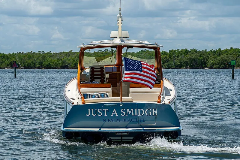 Slide: The Image of Hinckley Talaria 34 boat, 2013 model, with American flag, on water near lush shoreline. - 4
